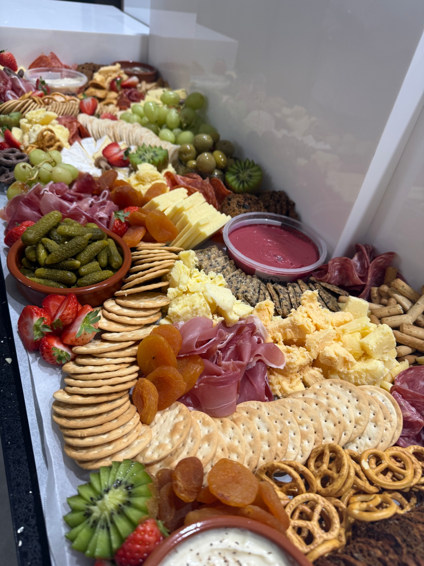 Long grazing spread with pickles, prosciutto and dips