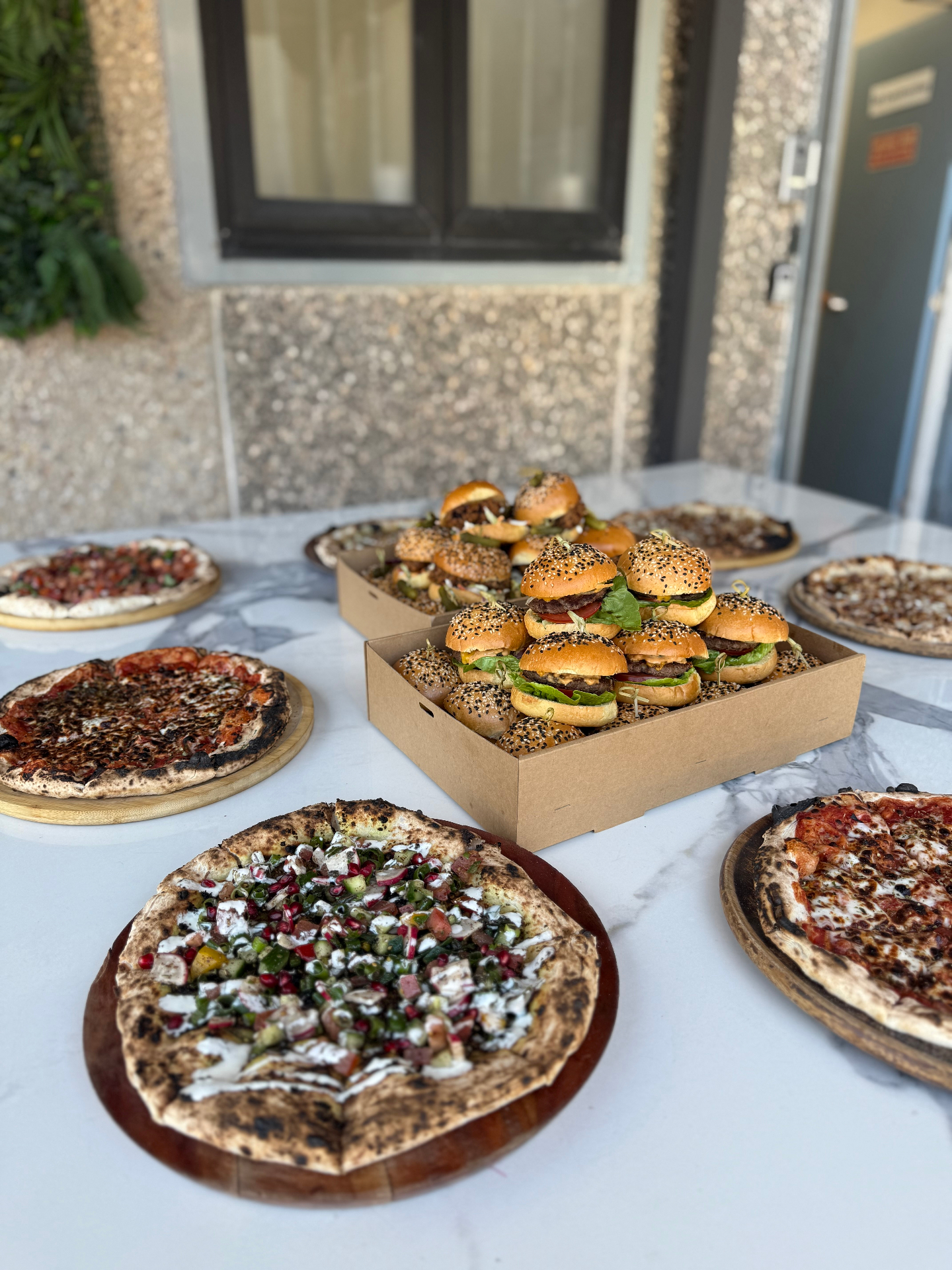Pizza and slider catering spread on a marble table