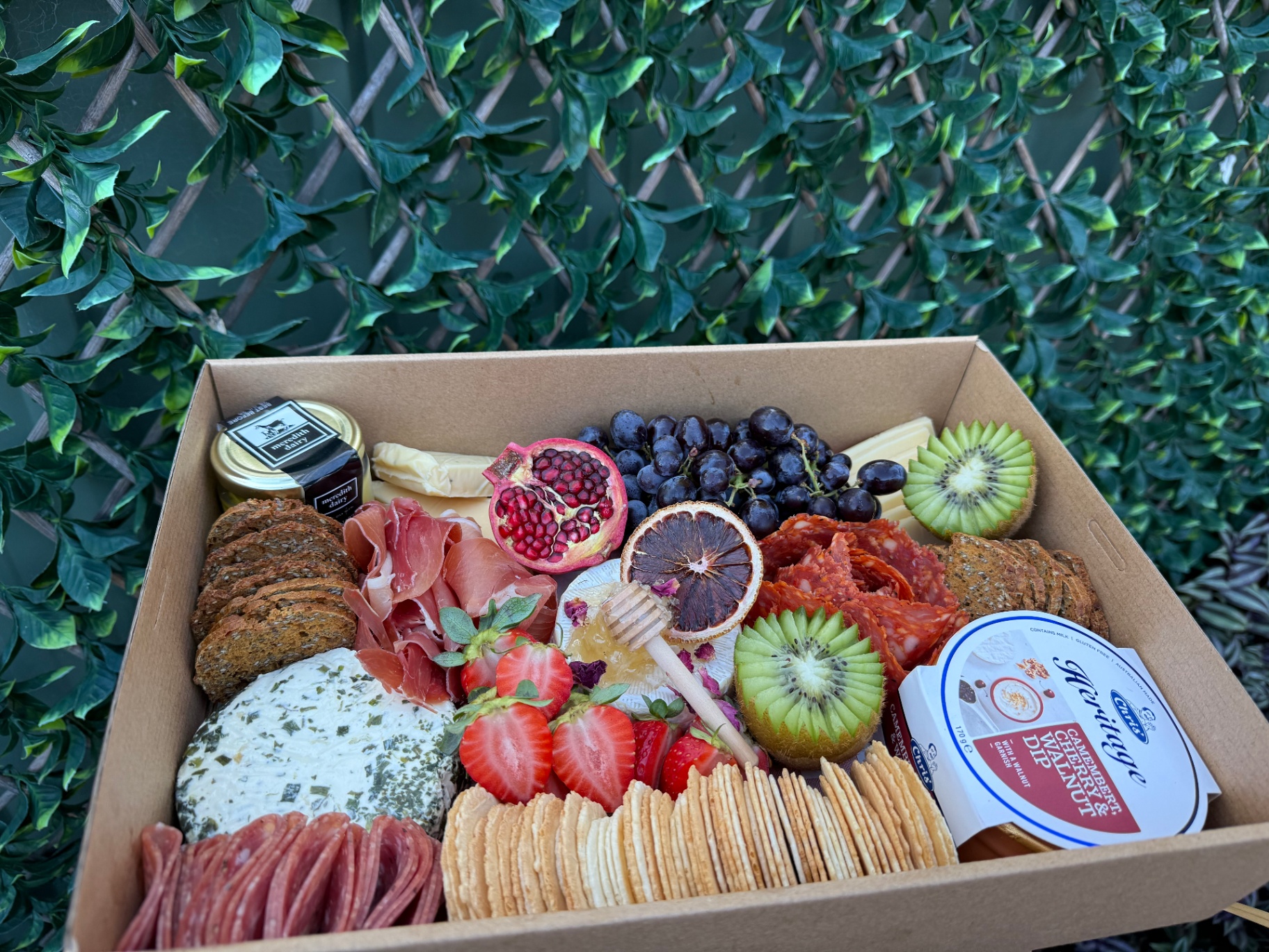 Charcuterie box with prosciutto, brie and seasonal fruit