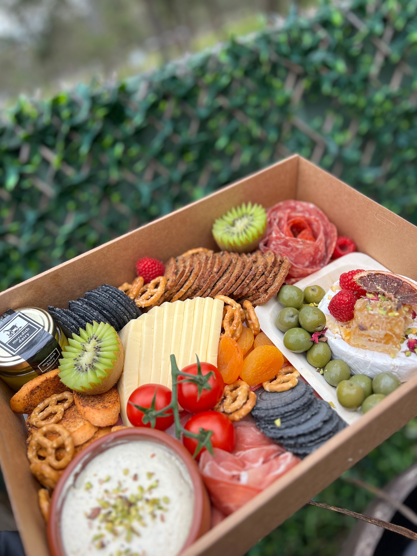 Charcuterie box with cheeses, olives and dips outdoors