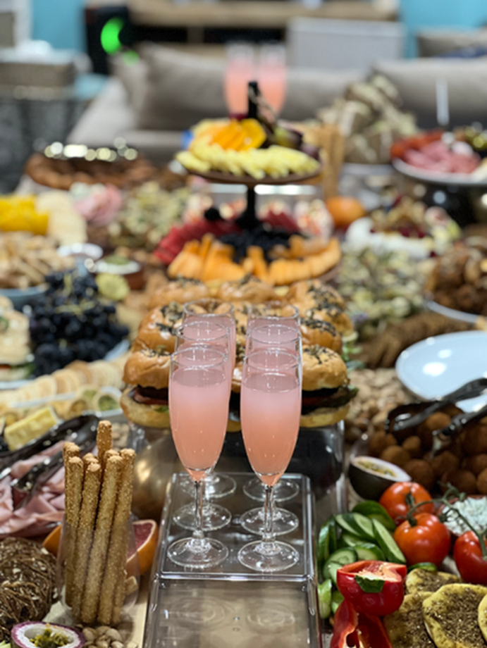 Styled grazing table with rose drinks, fruit and savoury bites